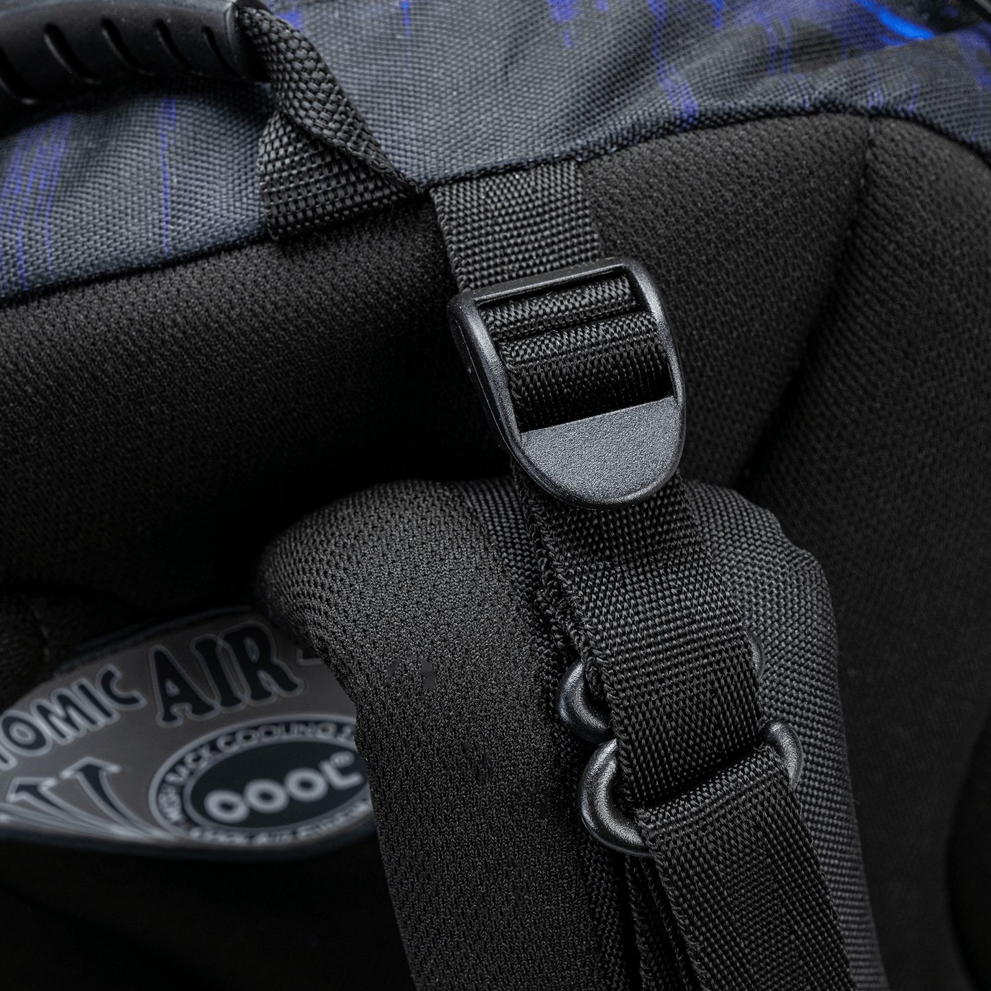 A close-up of a black bag strap adjuster and D-ring on a Savvy School bag with dark blue patterned fabric.