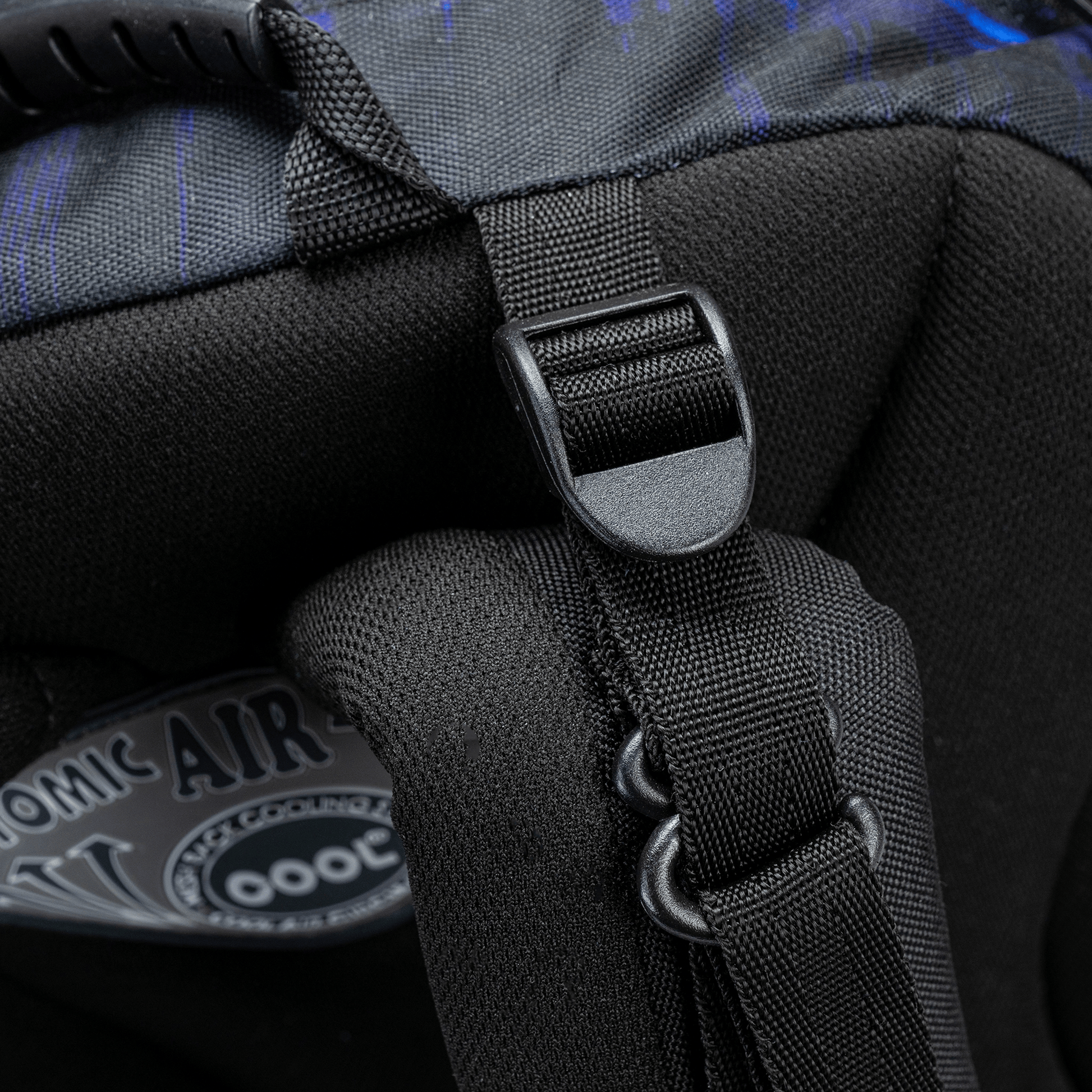 A close-up of a black bag strap adjuster and D-ring on a Savvy School bag with dark blue patterned fabric.