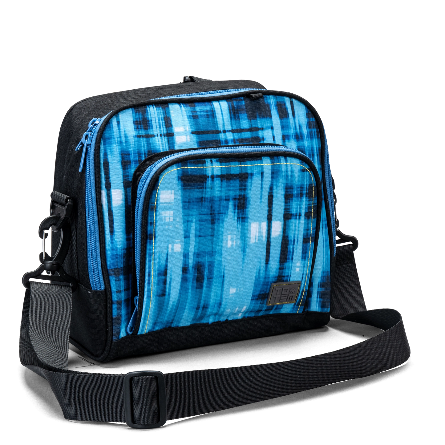 The front zip pocket on a blue geometric Totem lunch bag with contrast yellow stitching and logo patch.