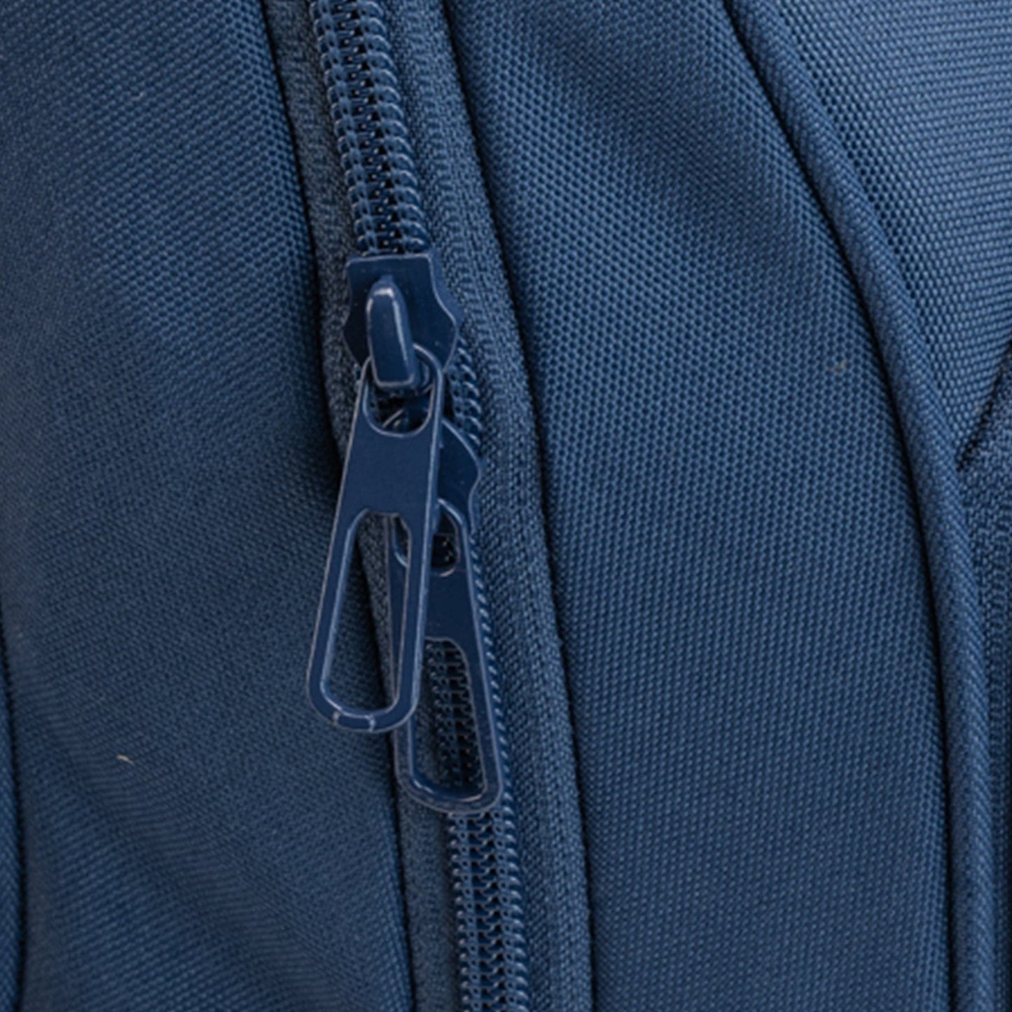 Close-up of a double zipper sliders on a navy Totem Bags backpack compartment.