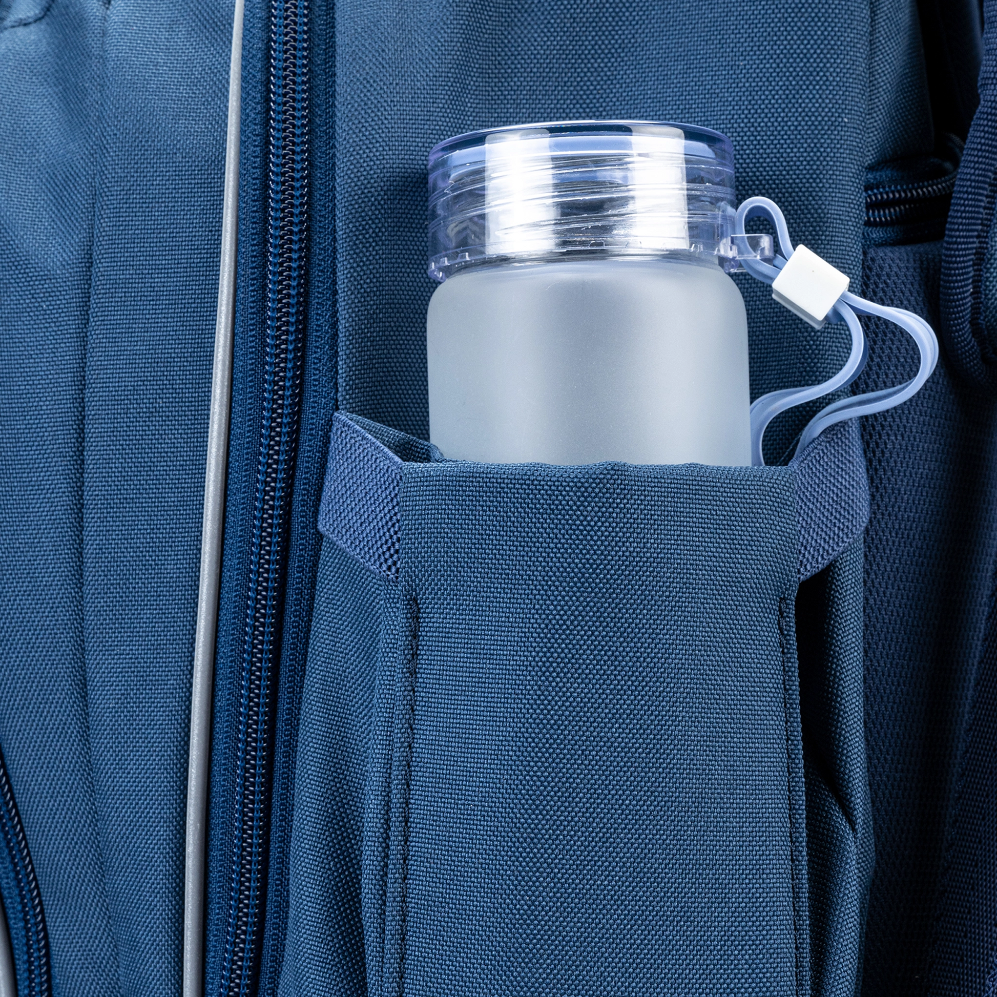 A Navy trolley bag with wheels and a handle that has a spot to carry/hold a water bottle.