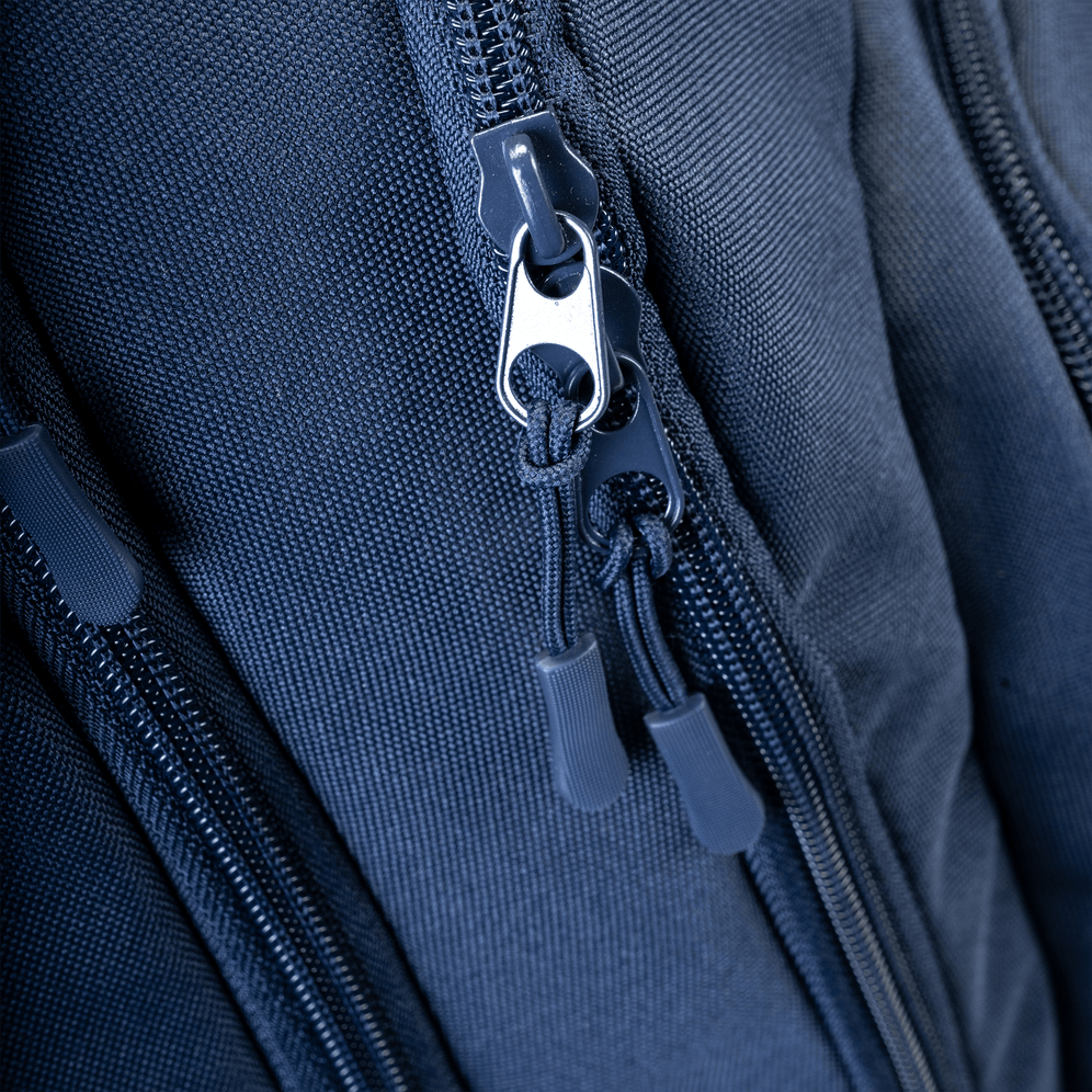A close-up of the navy backpack's dual zippers and textured fabric.
