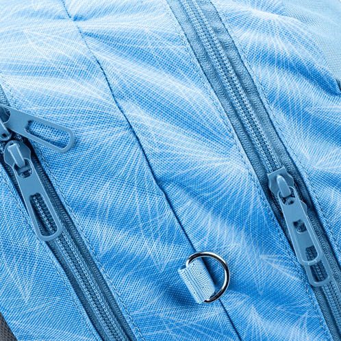 A close-up of a light blue Totem school bag showing double zippered compartments with a subtle starburst print fabric.