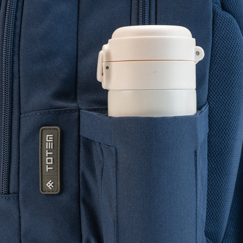 Side bottle pocket on a Totem backpack holding a water bottle, with Totem badge and durable fabric.